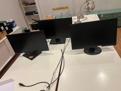 two computer monitors on a white desk in a room