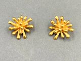 une paire de boucles d'oreilles en or posées sur une surface grise