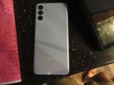 a white samsung phone sitting on a table next to a book