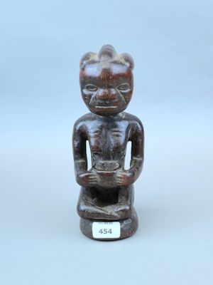 une image représentant une statue en bois d'un homme assis sur un tabouret