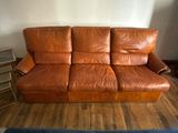 a brown leather couch that is sitting on a hard wood floor