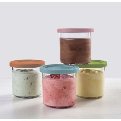 Quatre bocaux garnis de garnitures de différentes couleurs sont posés sur une table