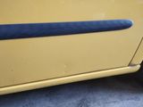 a close up of a yellow car with a blue door handle