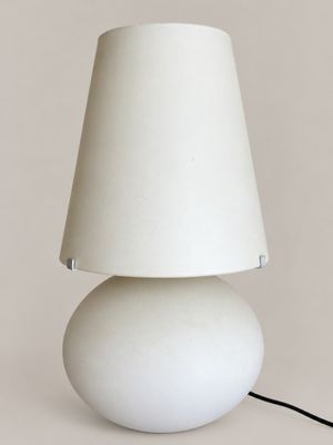 a white table lamp with a white shade on top of it