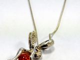 a silver necklace with a red bead on it