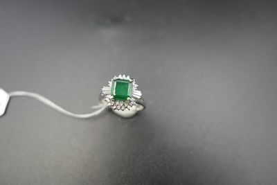an emerald and diamond ring on a black surface