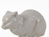 a small figurine of a cat sitting on a white surface