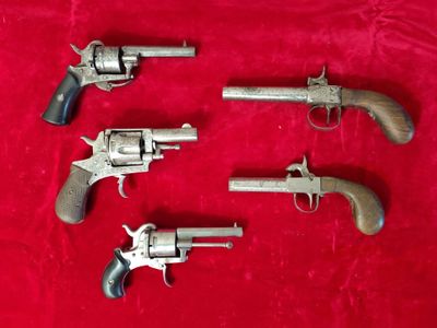 four old revolvers on a red velvet surface
