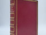 an old red book sitting on top of a white table