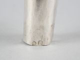 a silver cup on a white surface with a black lid