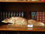 une statue représentant un chien allongé sur une étagère