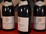 four bottles of wine are lined up on a red table