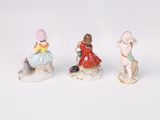 three figurines of children sitting on a rock