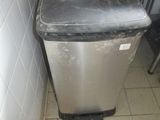 a trash can in the corner of a kitchen that is dirty