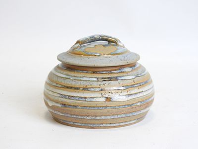 a ceramic jar with a lid on a white surface