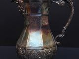 an antique silver plated coffee pot sitting on a black surface