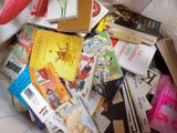 a pile of books on a bed next to a stuffed animal