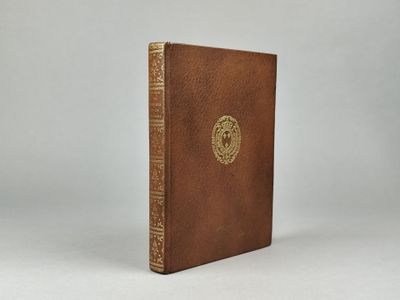 un livre en cuir marron orné d'un emblème doré