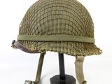 an old helmet is sitting on a stand on a white surface