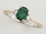 un gros plan sur une bague sertie d'une émeraude verte et de diamants