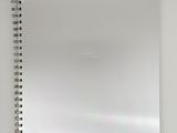a white spiral notebook with a blank page on top of it
