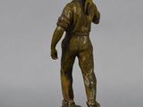 bronze figurine of a boy holding a baseball bat on a wooden base