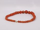 an orange beaded bracelet with a gold clasp on a white background