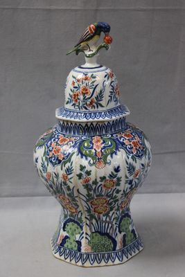 a bird sitting on top of a vase on a table