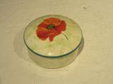 une petite boîte en verre ornée d'une fleur rouge