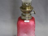 lampe à huile en verre rose surmontée d'un abat-jour en verre blanc