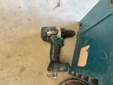 a cordless drill sitting on the floor next to a green box