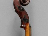 an old violin with a wooden bow on a gray background