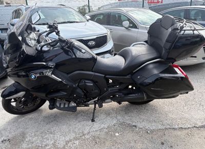 bmw motorcycle parked in a parking lot with other cars in the background