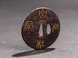 a small round metal object with asian writing on it