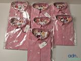 quatre t-shirts rayés rouges et blancs dans des sacs en plastique posés sur une table