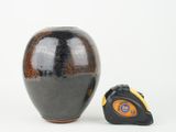 a black vase with a tape measure in front of it