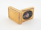 an image of a small gold box with a picture of a woman