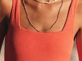 a woman in an orange tank top holding a surfboard