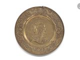 an image of a gold plate with a picture of a man on it