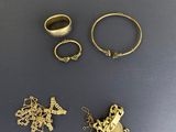 trois bagues en or et deux bagues en argent posées sur une table
