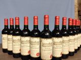 six bottles of red wine lined up in a row on a table