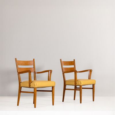 deux chaises en bois aux assises rembourrées de jaune, adossées à un mur gris