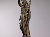 une statue représentant une femme tenant une lampe posée sur une table