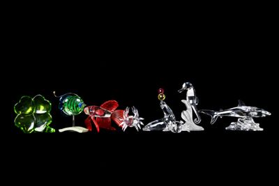 four different colored glass figurines on a black background