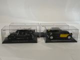 two black and yellow model cars in clear cases on a white surface