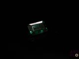 a close up of a green emerald stone on a black surface