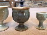 three cups sitting on a table with a stone wall in the background