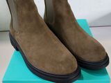 a pair of brown sued chelsea boots on top of a blue box