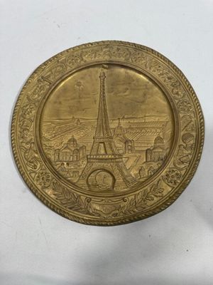 a close up of a gold plate with a picture of the eiffel tower