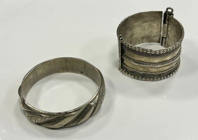 deux bracelets en argent et une bague en argent posés sur une surface blanche